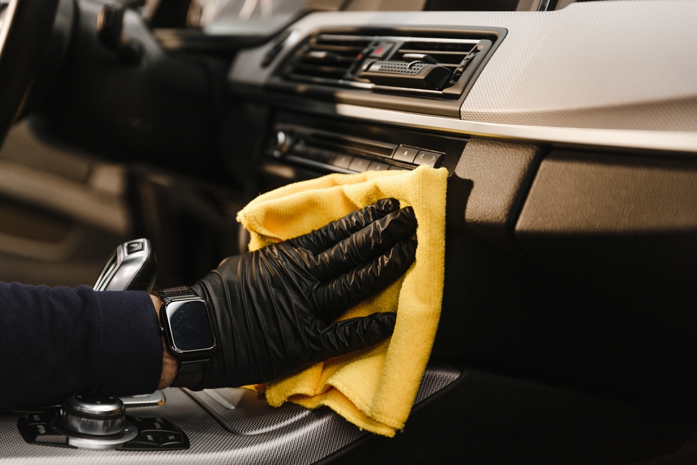 A detailer hand-finishing a freshly cleaned car with a microfibre cloth